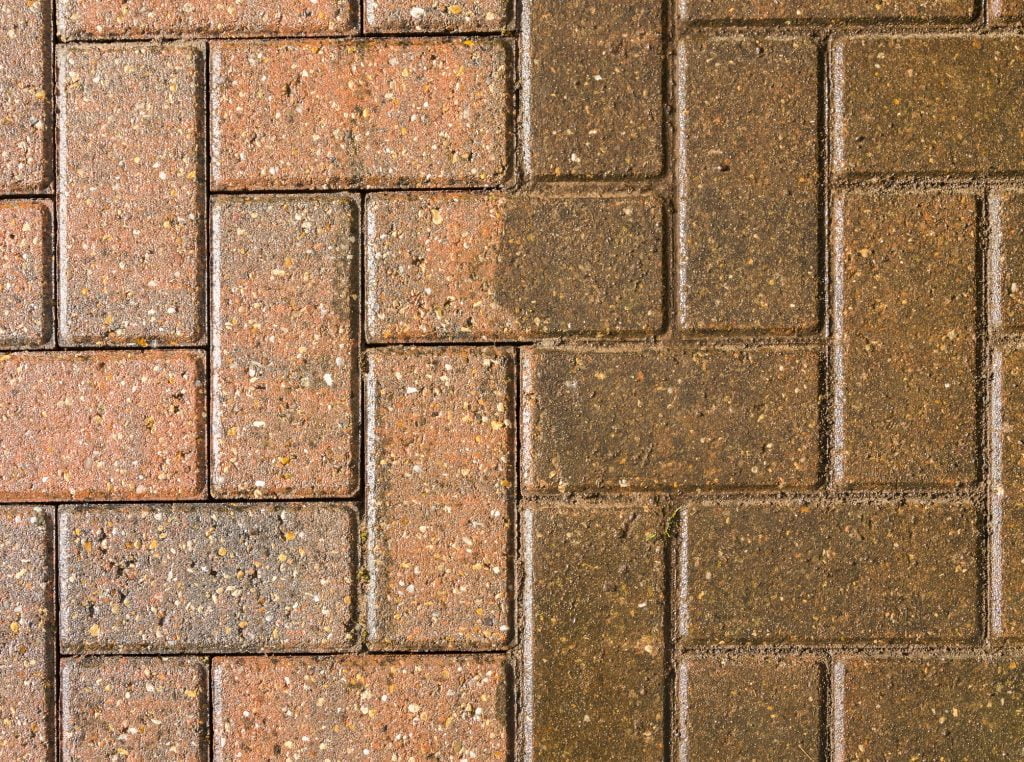 Side by side comparison of brick pavers being pressure cleaned